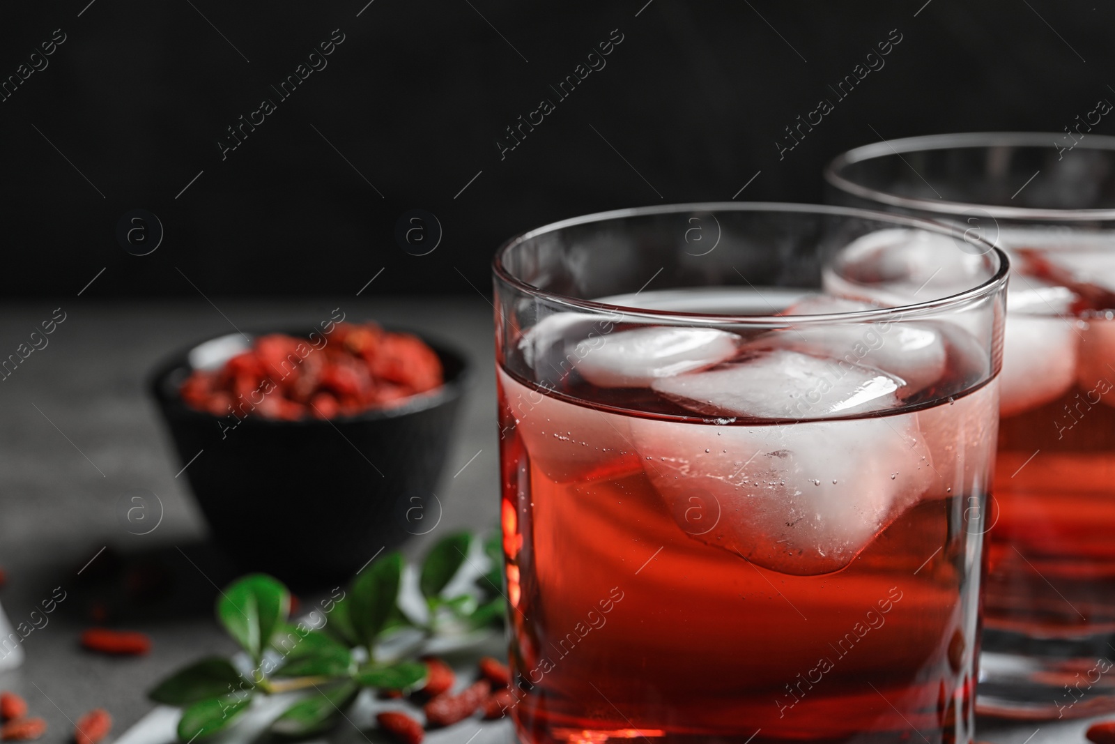 Photo of Healthy goji juice with ice in glasses on table, closeup