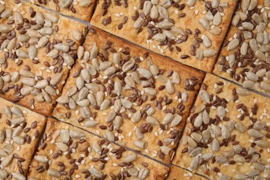 Photo of Cereal crackers with flax, sunflower and sesame seeds as background, top view