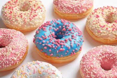 Photo of Delicious glazed doughnuts with sprinkles on light background