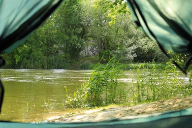 Photo of Calm river with forest on bank, view from camping tent
