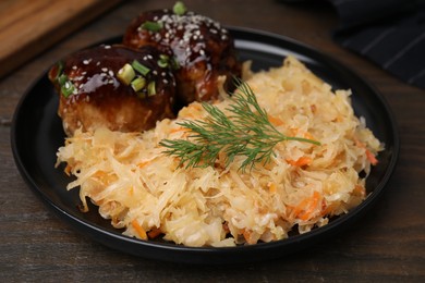 Photo of Plate with sauerkraut and chicken on wooden table, closeup