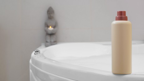 Photo of Beige bottle of bubble bath on tub indoors, space for text