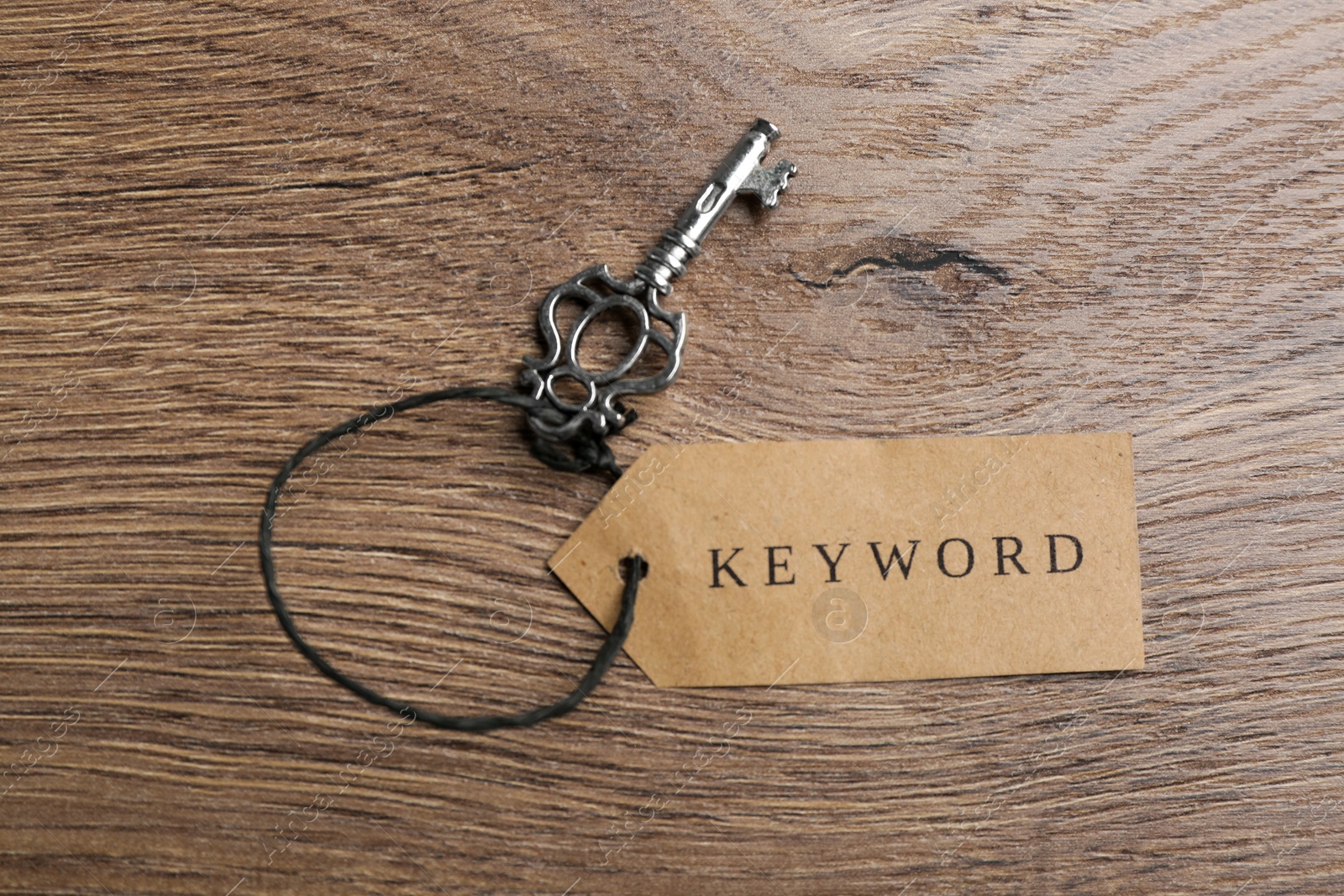 Photo of Vintage key and tag wIth word KEYWORD on wooden table, top view