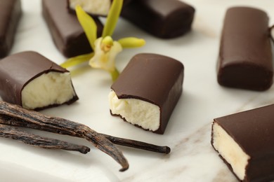 Photo of Glazed curd cheese bars, vanilla pods and flower on white board, closeup