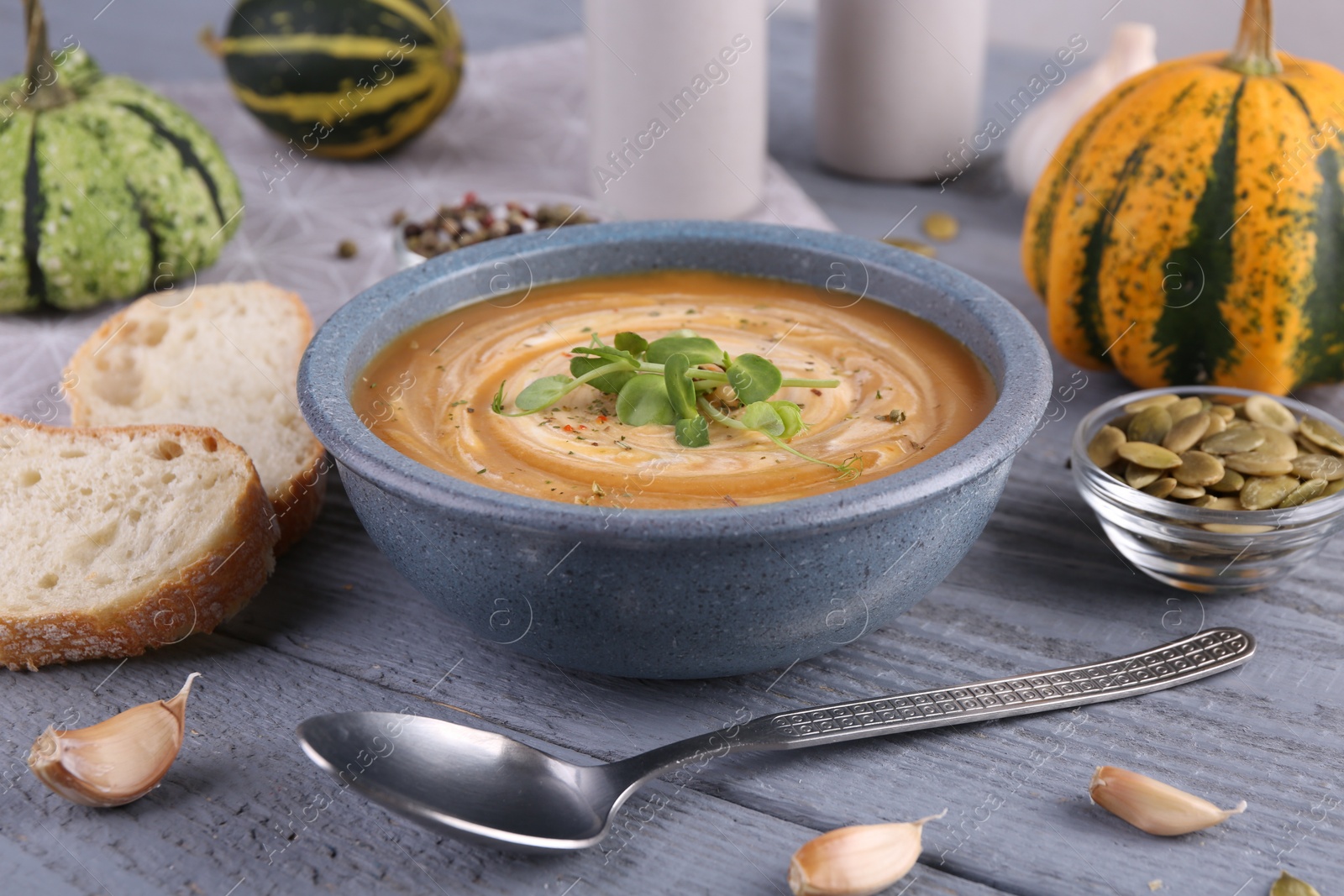 Photo of Tasty pumpkin soup served on grey wooden table