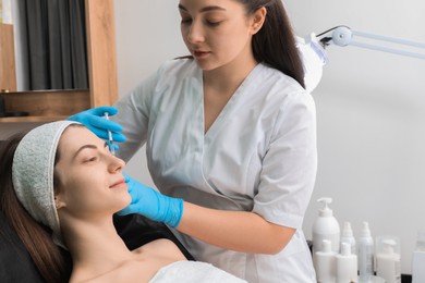 Photo of Cosmetologist giving facial injection to patient in clinic. Cosmetic surgery