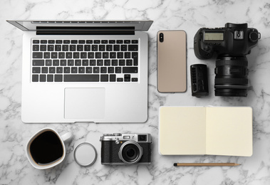 Photo of Flat lay composition with laptop, cameras and smartphone on white marble table. Designer's workplace
