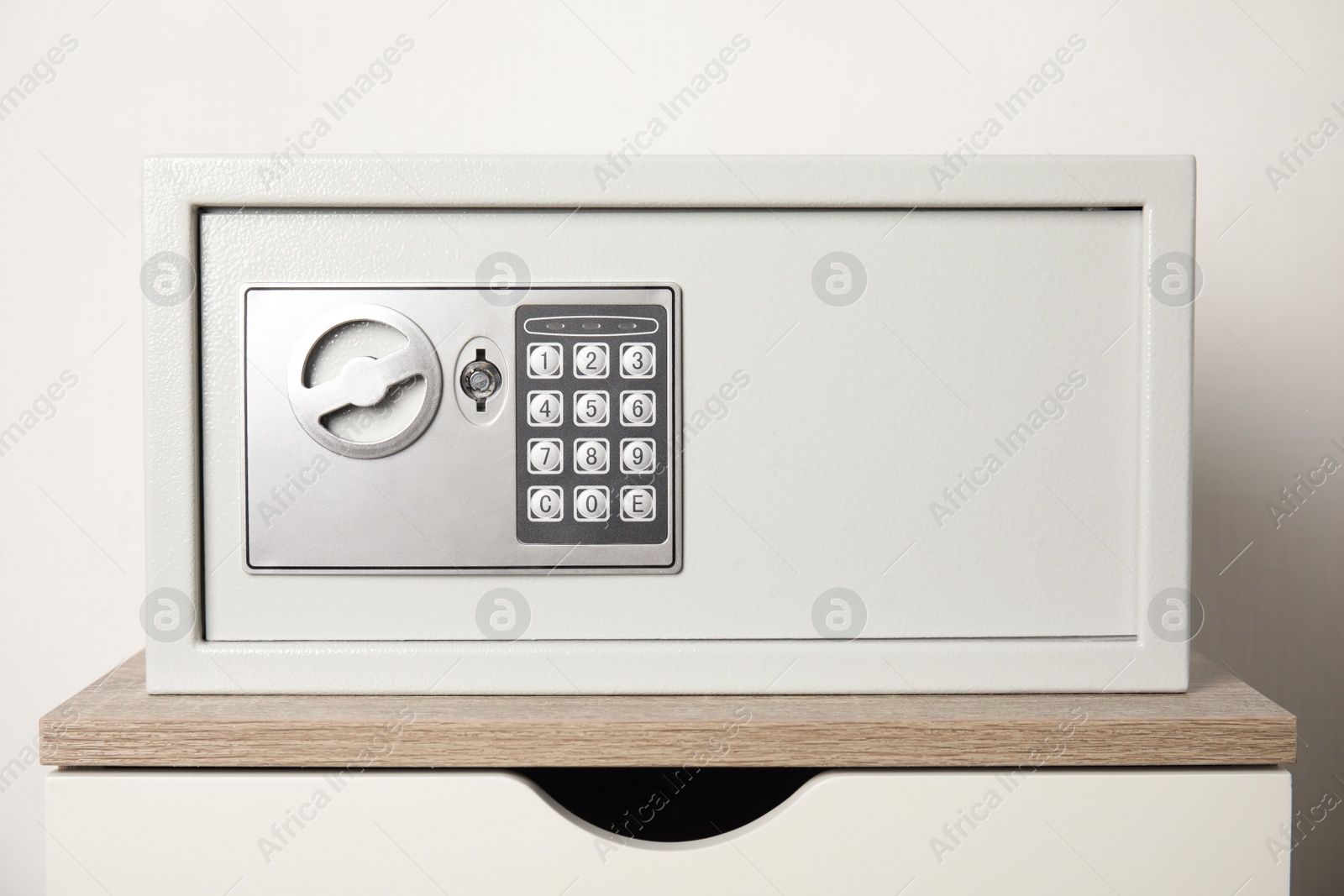 Photo of Closed steel safe on wooden table against white background