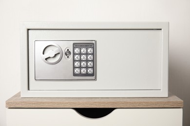 Closed steel safe on wooden table against white background