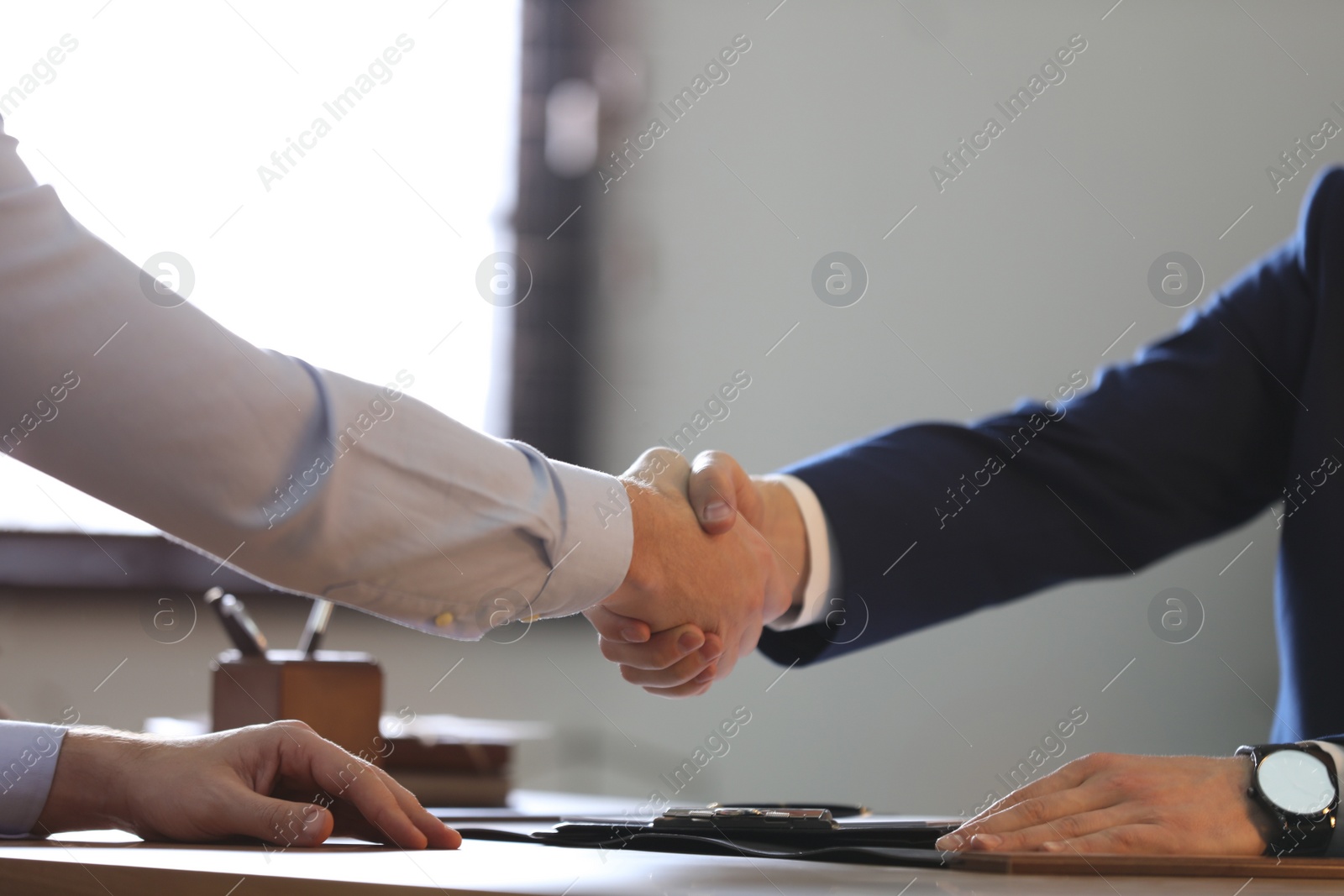 Photo of Male lawyer shaking hands with client in office, closeup