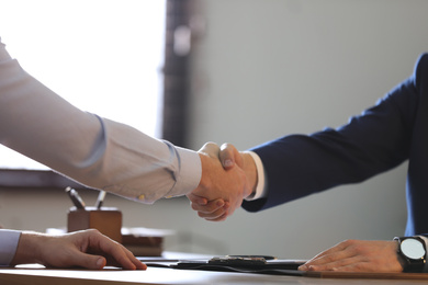 Male lawyer shaking hands with client in office, closeup