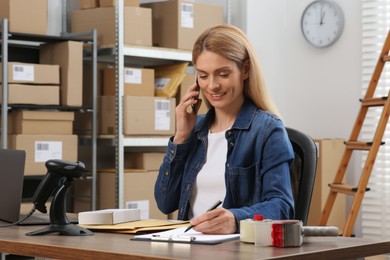 Photo of Seller talking on phone while working in office. Online store