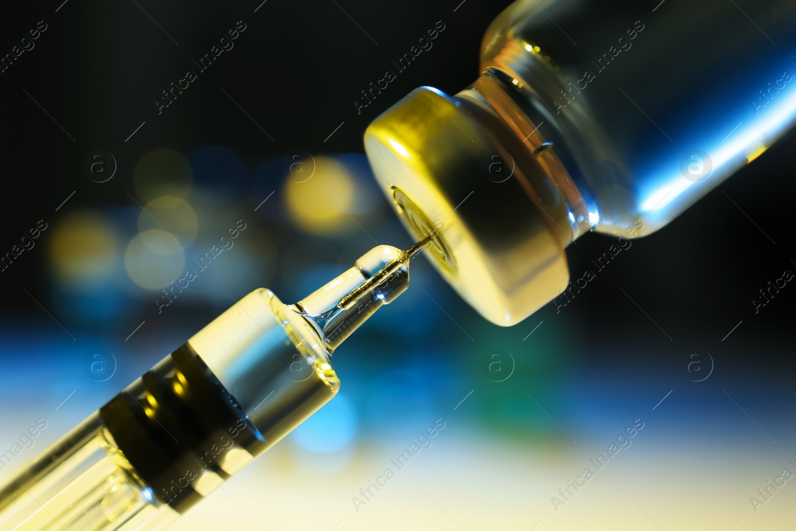 Photo of Filling syringe with vaccine from vial on blurred background, closeup