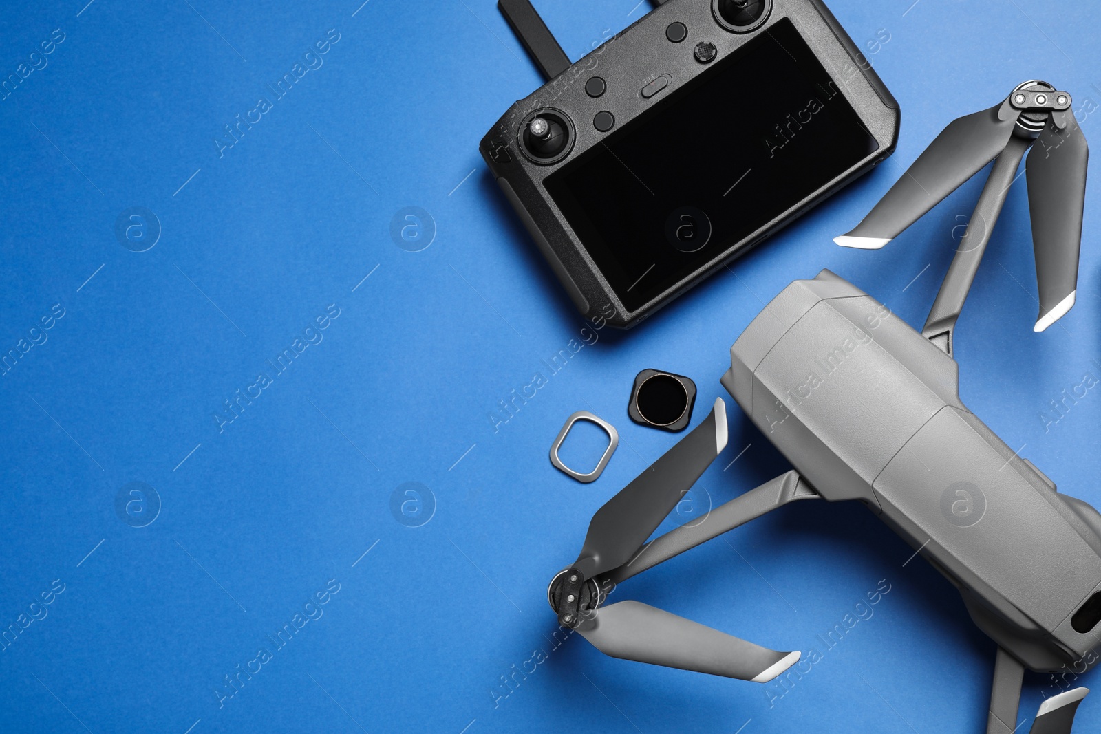 Photo of Modern drone with camera and video production equipment on blue background, flat lay. Space for text