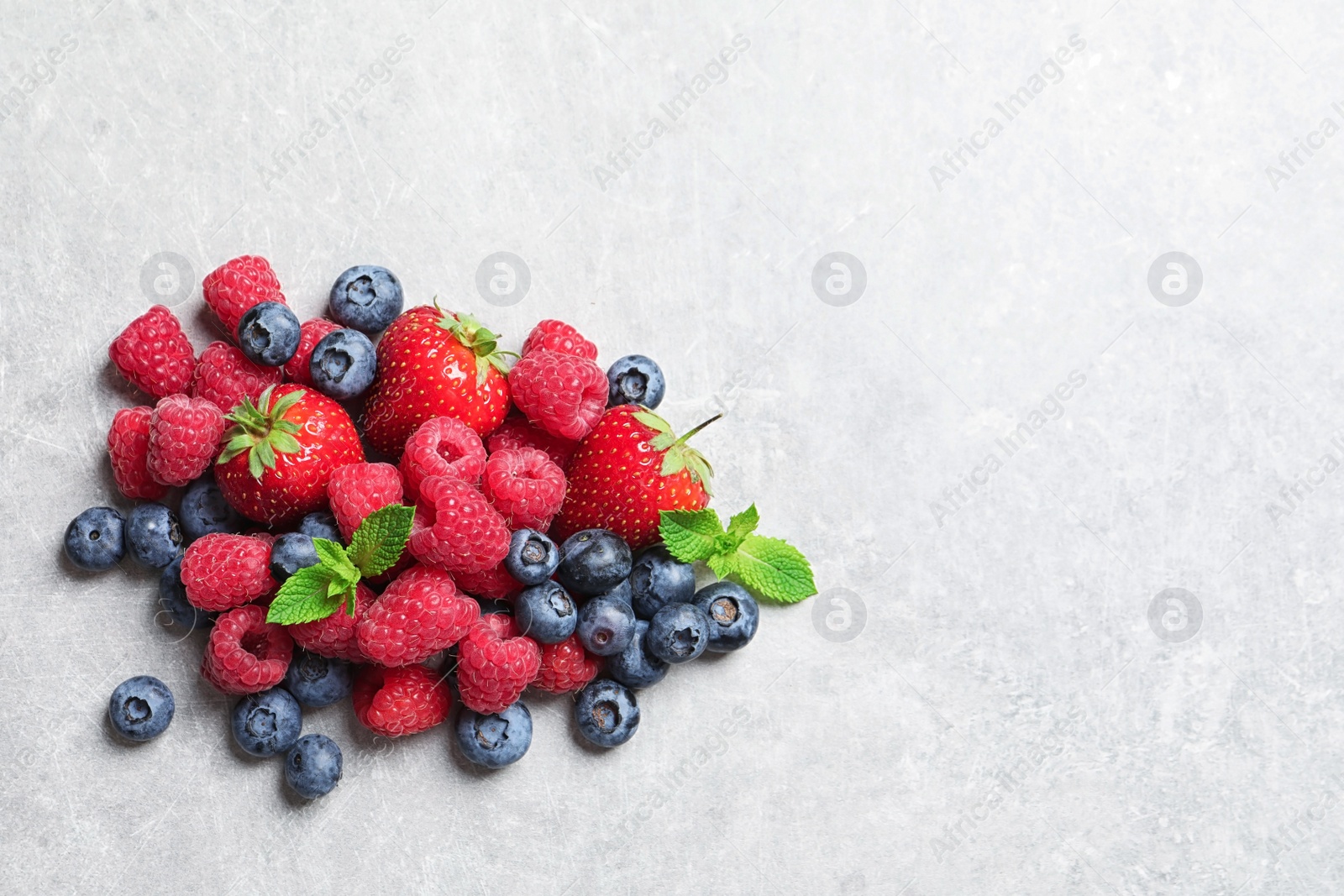 Photo of Raspberries, strawberries and blueberries on table, top view