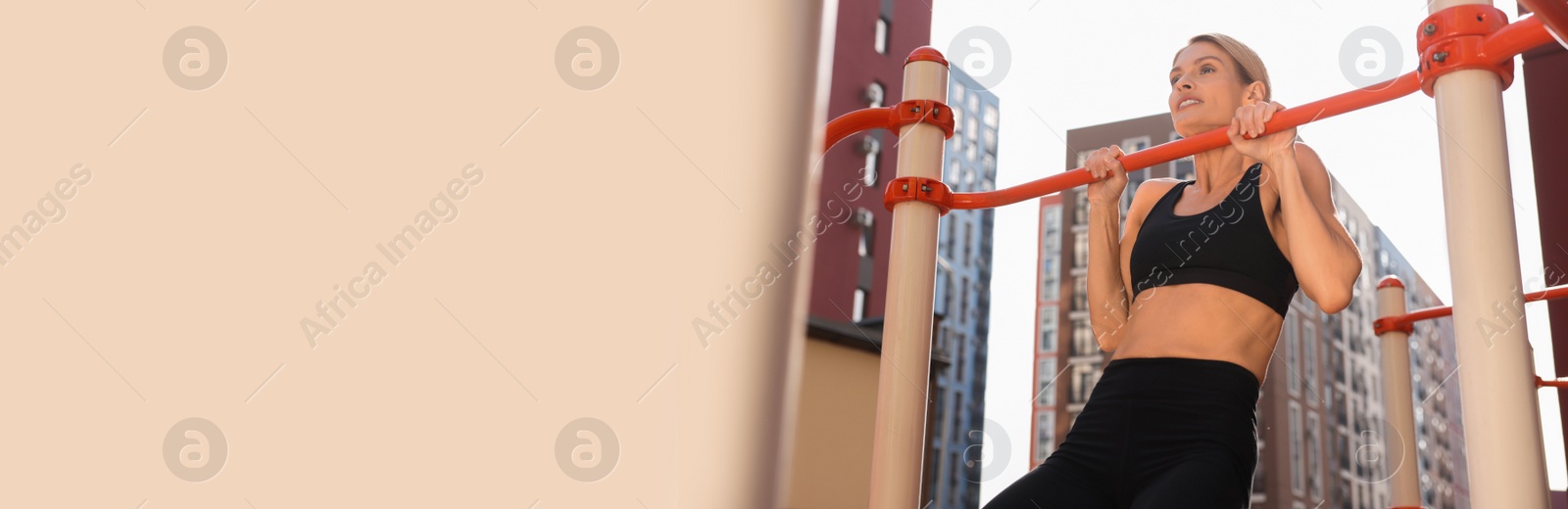 Image of Happy woman doing pull-ups at outdoor gym, space for text. Banner design