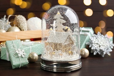 Photo of Beautiful Christmas snow globe and festive decor on wooden table