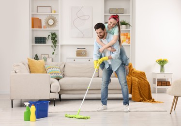 Photo of Spring cleaning. Couple having fun while tidying up living room