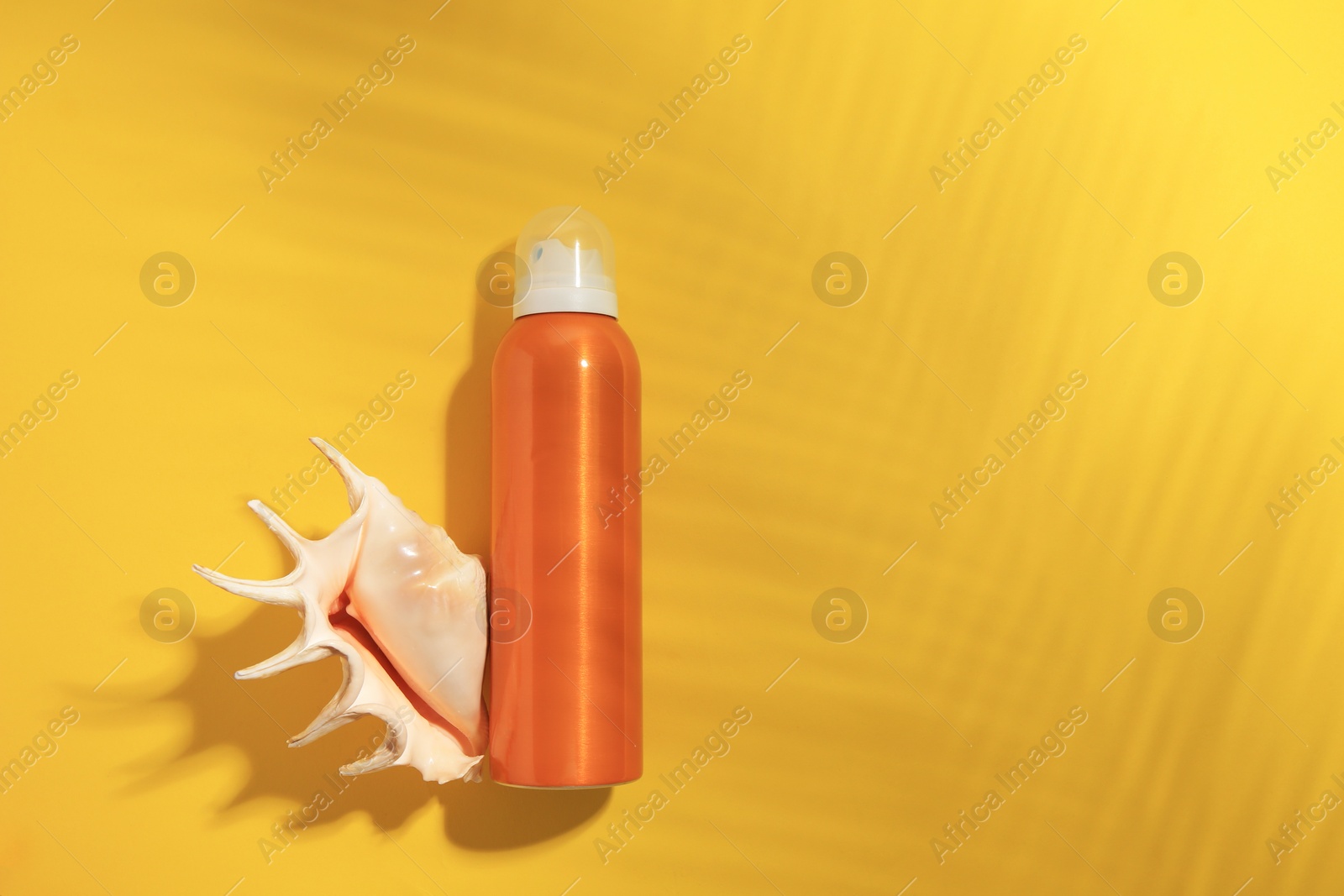 Photo of Sunscreen and seashell on yellow background, flat lay and space for text. Sun protection care