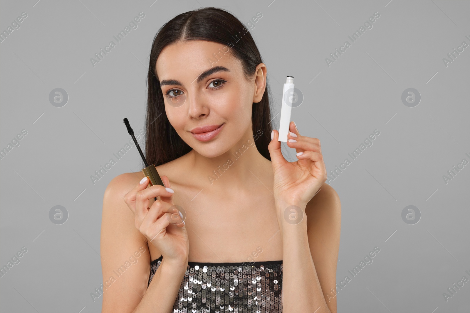 Photo of Beautiful young woman with mascara on grey background