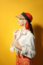 Photo of Beautiful young woman with bright dyed hair on orange background