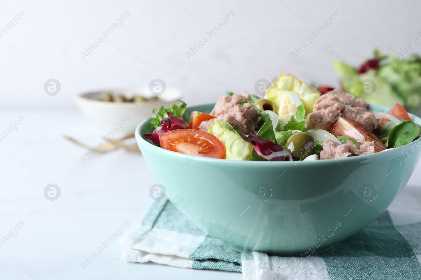 Photo of Bowl of delicious salad with canned tuna and vegetables on white table, space for text