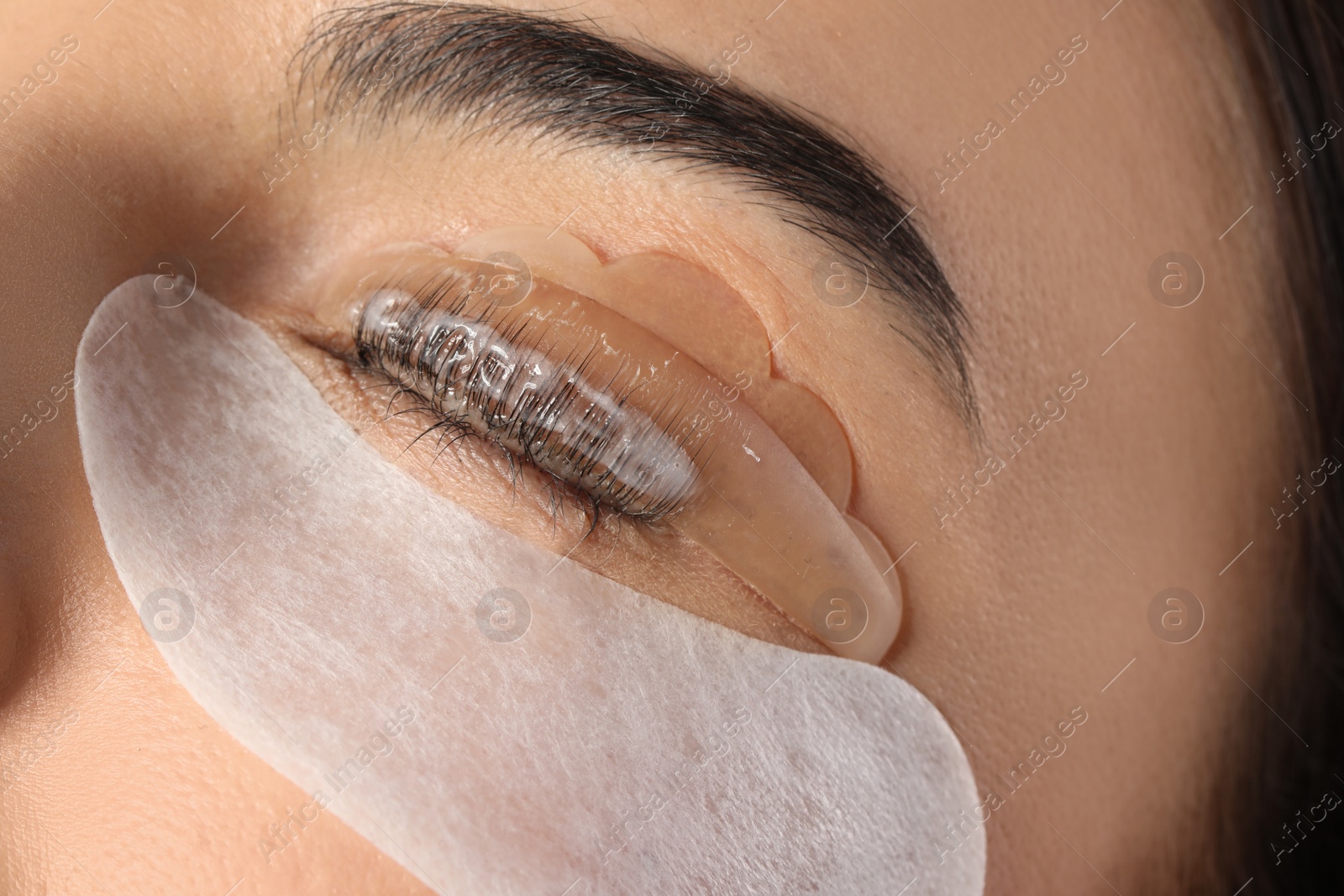 Photo of Young woman undergoing eyelash lamination, closeup. Professional service