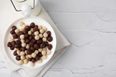 Photo of Breakfast cereal. Tasty corn balls with milk in bowl on white textured table, top view. Space for text