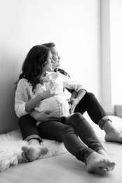 Pregnant woman with her husband indoors, black and white effect