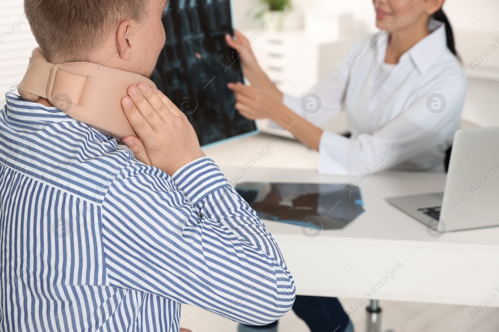 Photo of Doctor with neck MRI image consulting patient in clinic, closeup. Space for text