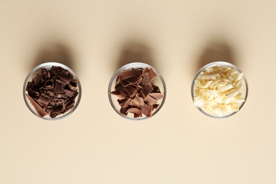 Bowls with different chocolate curls on color background, top view