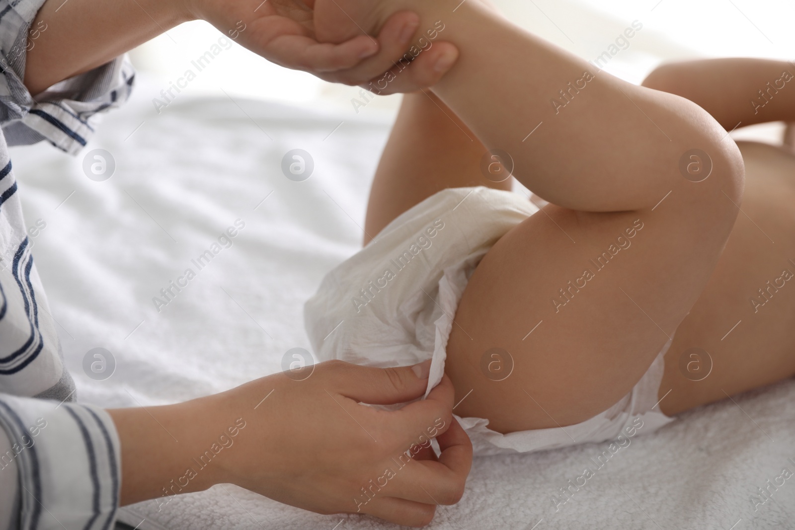 Photo of Mother changing baby's diaper on table at home, closeup