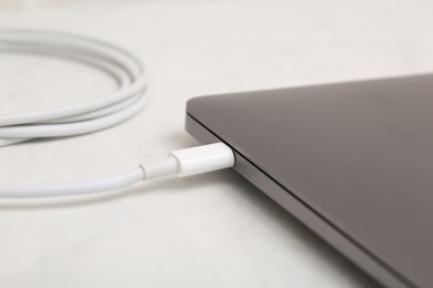 Photo of Charge cable connected to laptop on light table, closeup