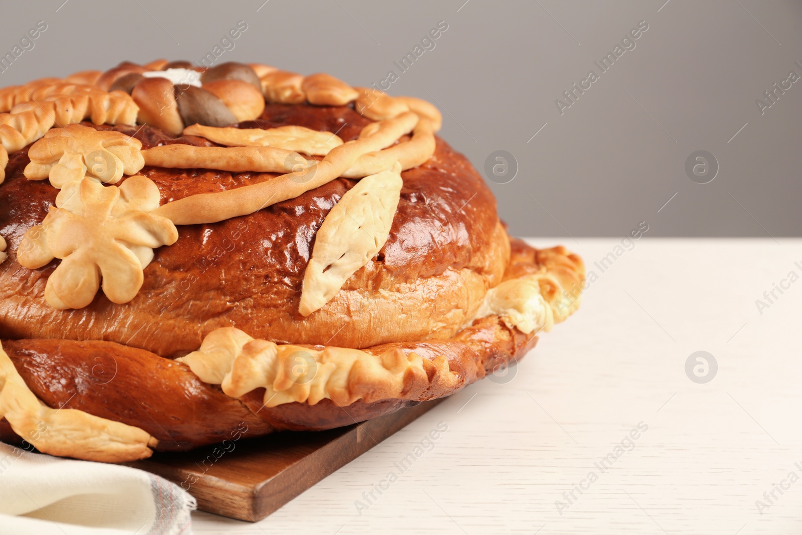 Photo of Korovai on white table, space for text. Ukrainian bread and salt welcoming tradition