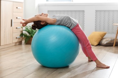 Little cute girl doing exercises with fitness ball at home