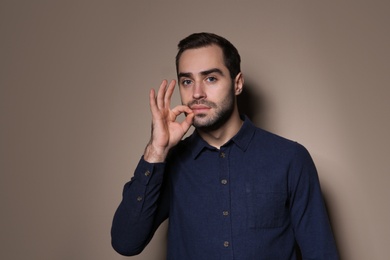 Photo of Man zipping his mouth on color background. Using sign language