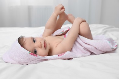 Photo of Cute little baby in hooded towel after bathing on bed at home