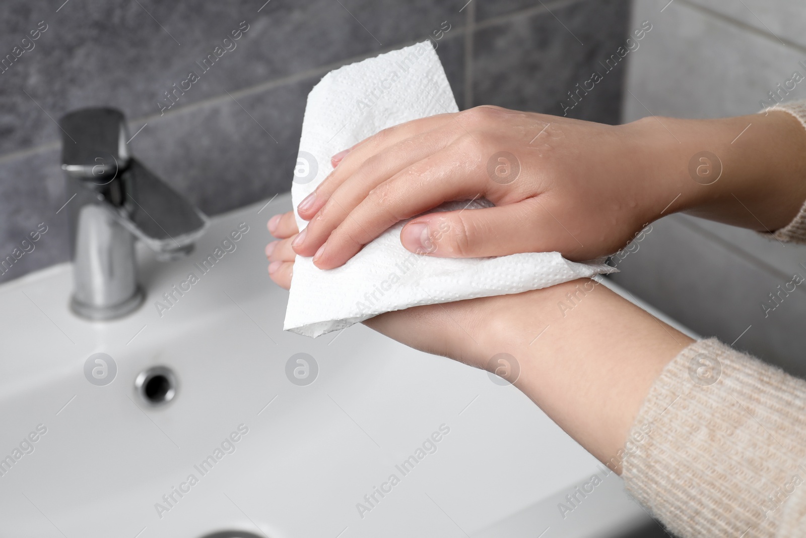 Photo of Woman wiping hands with paper towel in bathroom, closeup