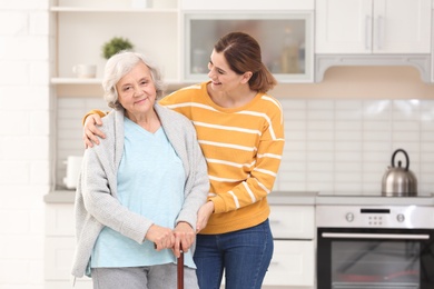 Photo of Elderly woman with female caregiver in kitchen. Space for text