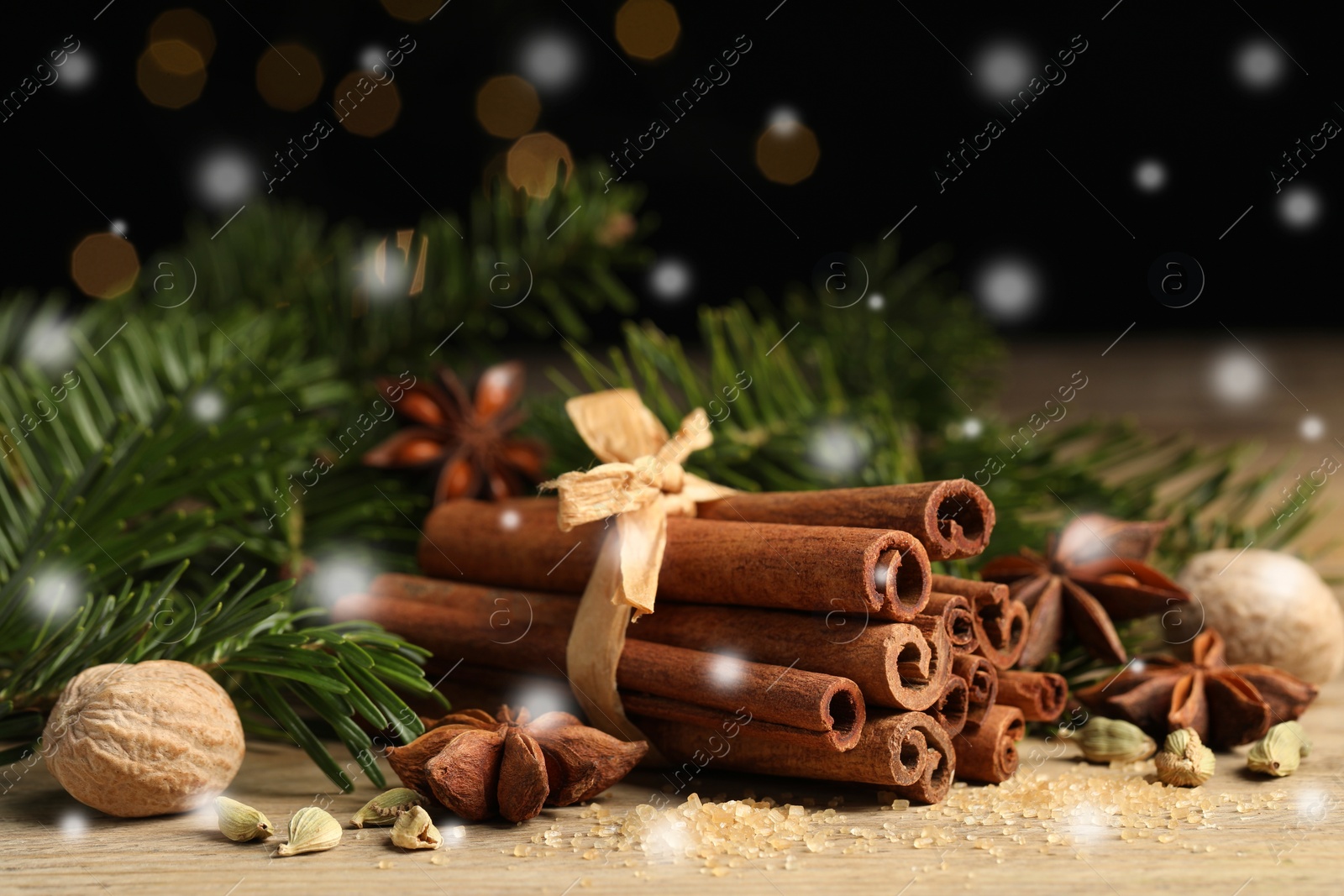 Image of Different spices and fir tree branches on wooden table, closeup. Cinnamon, anise, cardamom, nutmegs