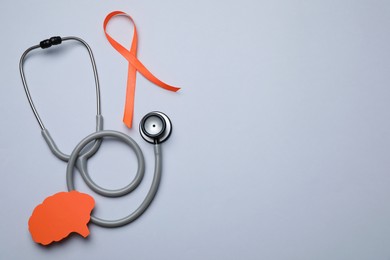 Orange ribbon, stethoscope and paper brain cutout on light grey background, flat lay with space for text. Multiple sclerosis awareness