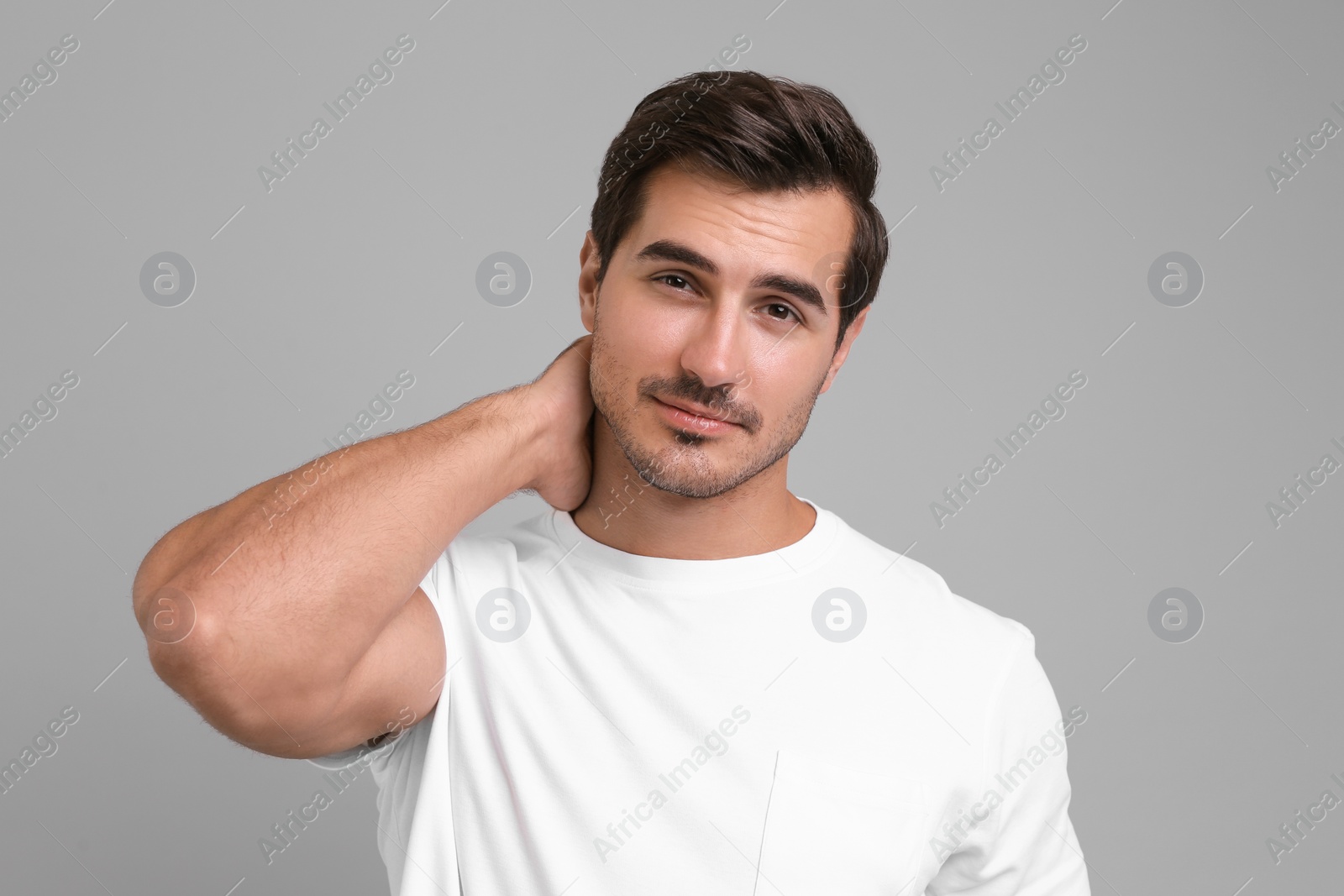 Photo of Portrait of handsome young man in white t-shirt on grey background