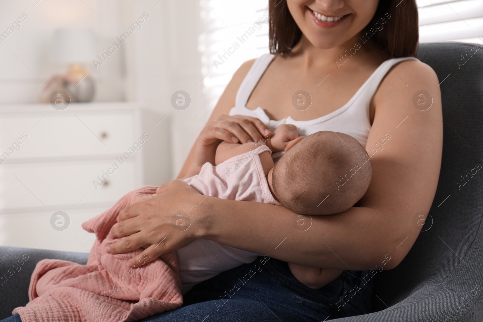 Photo of Young woman breastfeeding her little baby at home, closeup