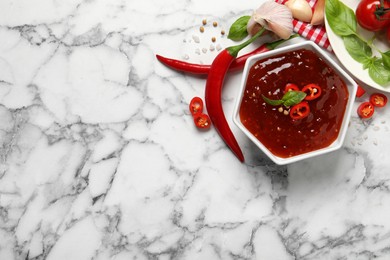 Spicy chili sauce and ingredients on white marble table, flat lay. Space for text