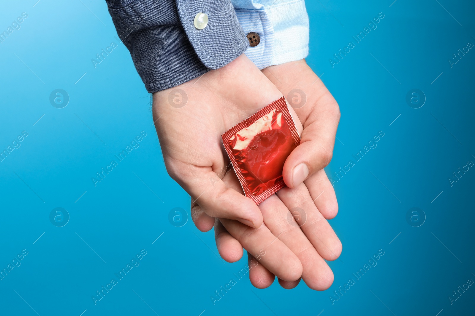 Photo of Gay couple with condom on light blue background, closeup