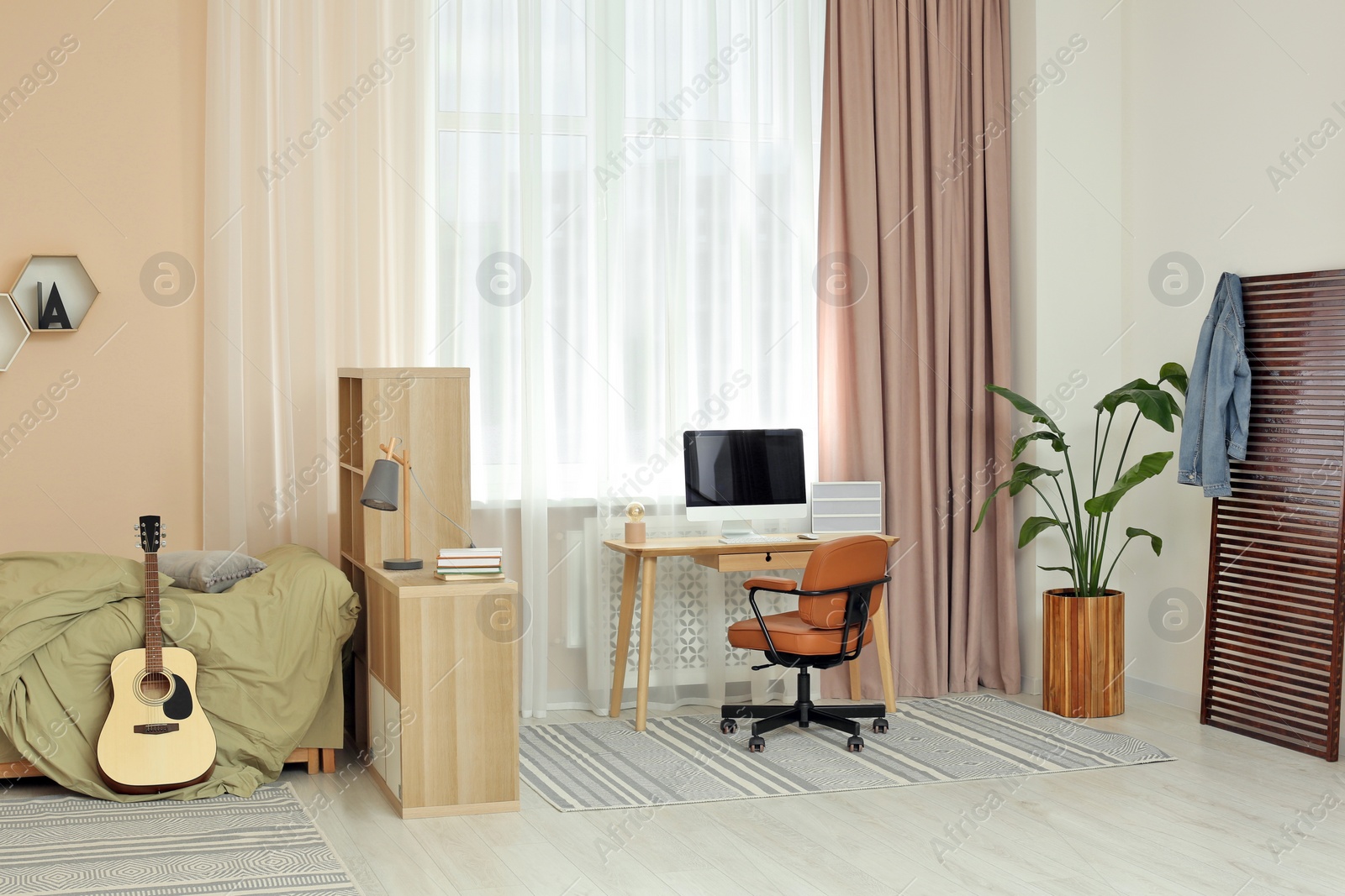 Photo of Stylish teenager's room interior with workplace beautiful houseplant and guitar