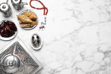 Flat lay composition with Arabic lantern and snacks on white marble table . Space for text