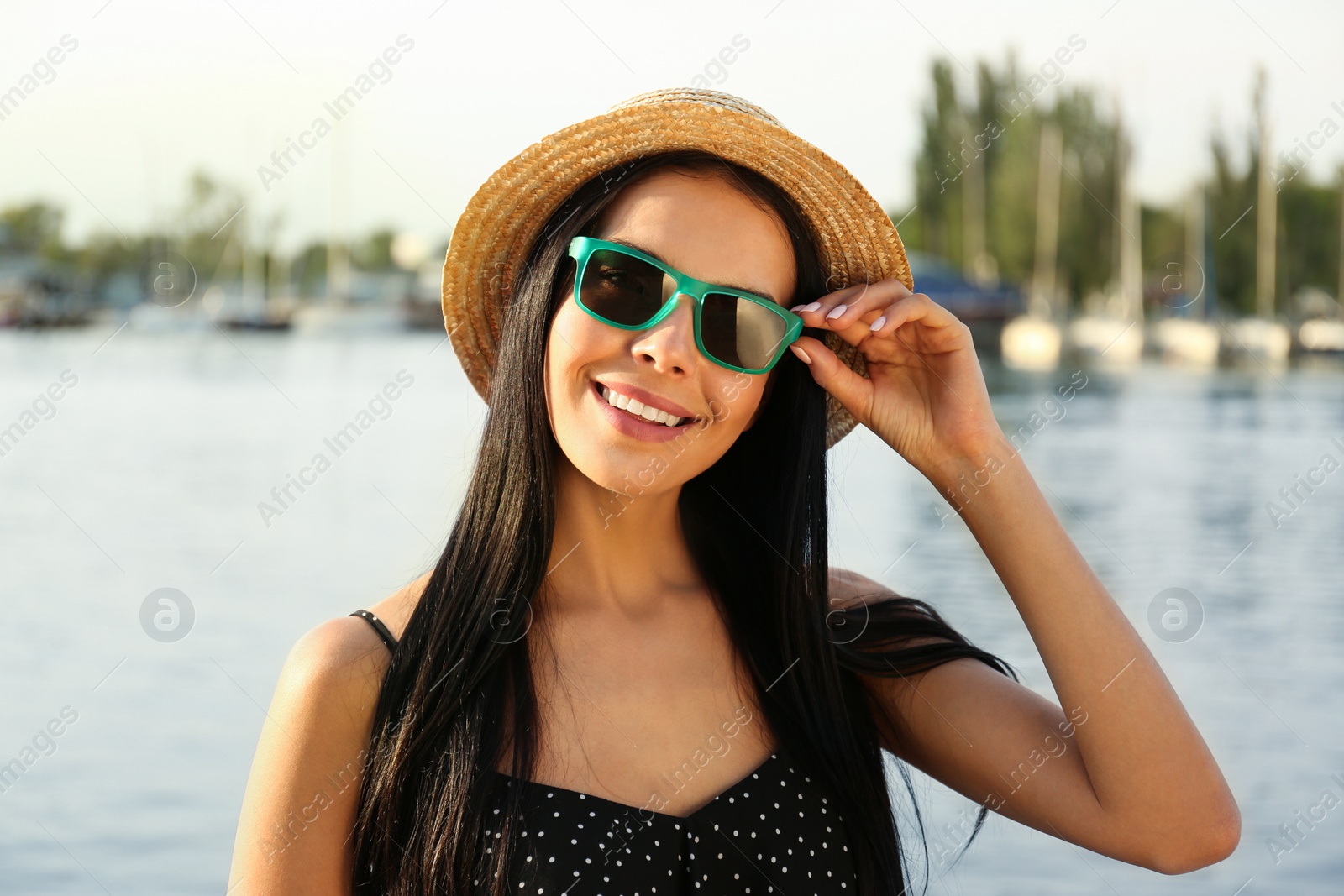 Photo of Beautiful young woman wearing stylish sunglasses near river