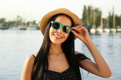 Beautiful young woman wearing stylish sunglasses near river