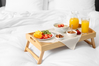 Photo of Wooden tray with tasty breakfast on bed at home